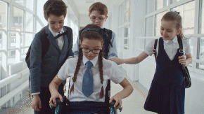 School children walking with girl in wheelchair